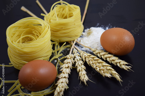 Pasta from durum wheat,the ears of corn on a black background.