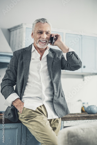 Handsome man smiling broadly while speaking by the phone