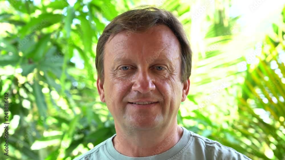 Portrait of a middle aged man resting on a background of green leaves in nature, close up Portrait of a middle aged man resting on a background of green leaves in nature, close up