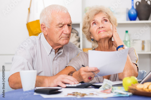 Worried mature man and woman analyzing bills