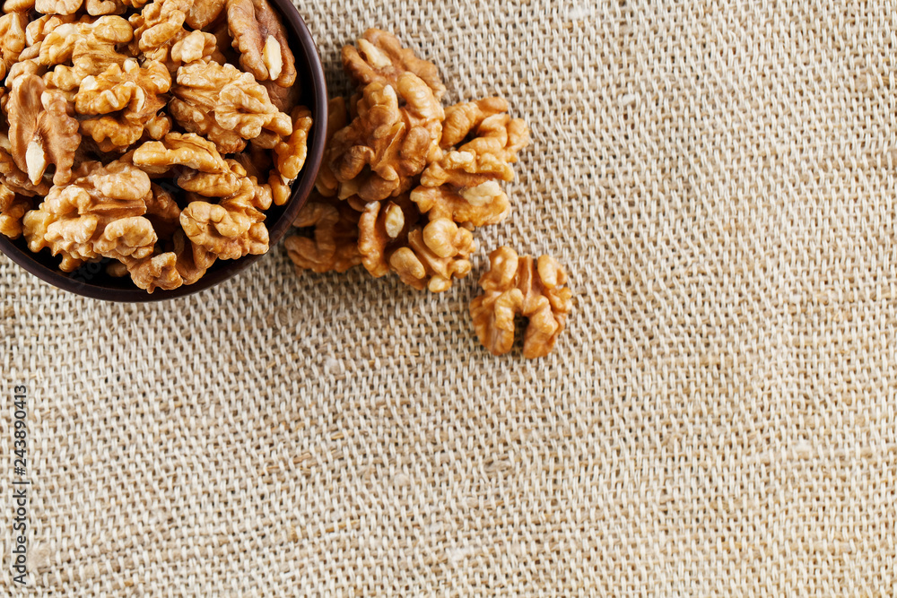 Peeled walnuts in a wooden, dark brown cup on a burlap cloth. Peeled walnuts in a wooden, dark brown cup on a burlap cloth.