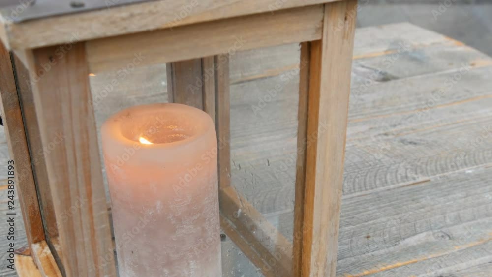 Large wax candle in a stylish wooden candlestick on the table of a street cafe. Large wax candle in a stylish wooden candlestick on the table of a street cafe.