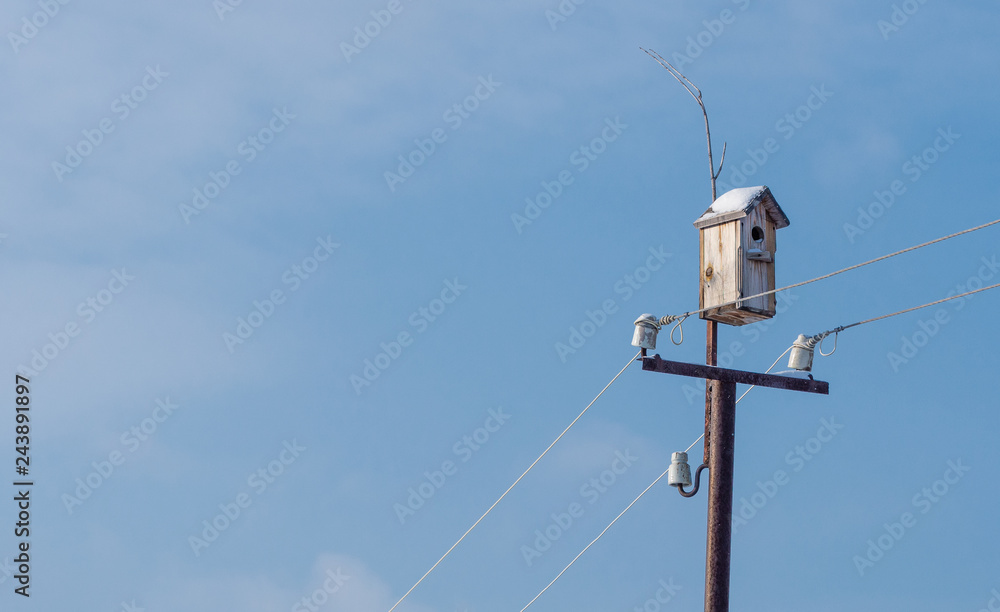 Birdhouse in winter on a pole with wires Birdhouse in winter on a pole with wires