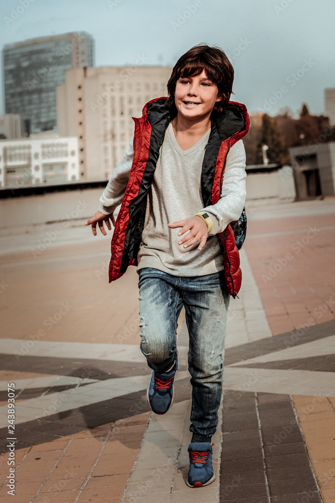 Obraz premium Smiling energetic kid running outdoor after school