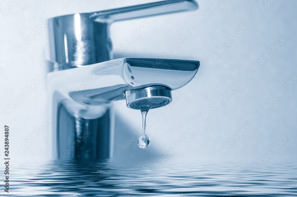 Faucet with water drop close up on blue background Faucet with water drop close up on blue background