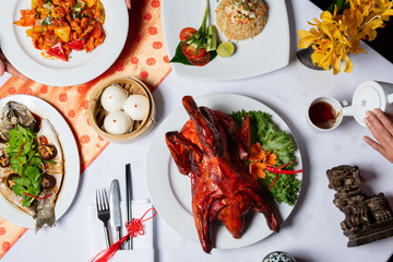 Concept picture for Chinese new year table set up and Chinese dishes. Men and Women are serving tea and crispy duck.