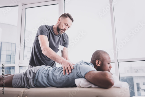 Attentive bearded man doing massage to his patient