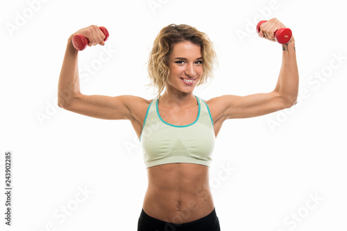 Beautiful young fit girl working out biceps with dumbbells
