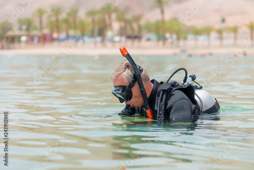 Underwater diver in basic equipment dives into the sea. Lessons of underwater diving. Popular water sport and leisure activity