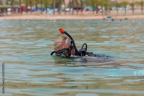 Underwater diver with breathing apparatus dives into the sea. Popular water sport and leisure activity