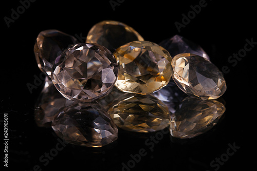 Group of big white and yellow transparent diamond shaped stones on a reflecting surface surrounded with a black studio background