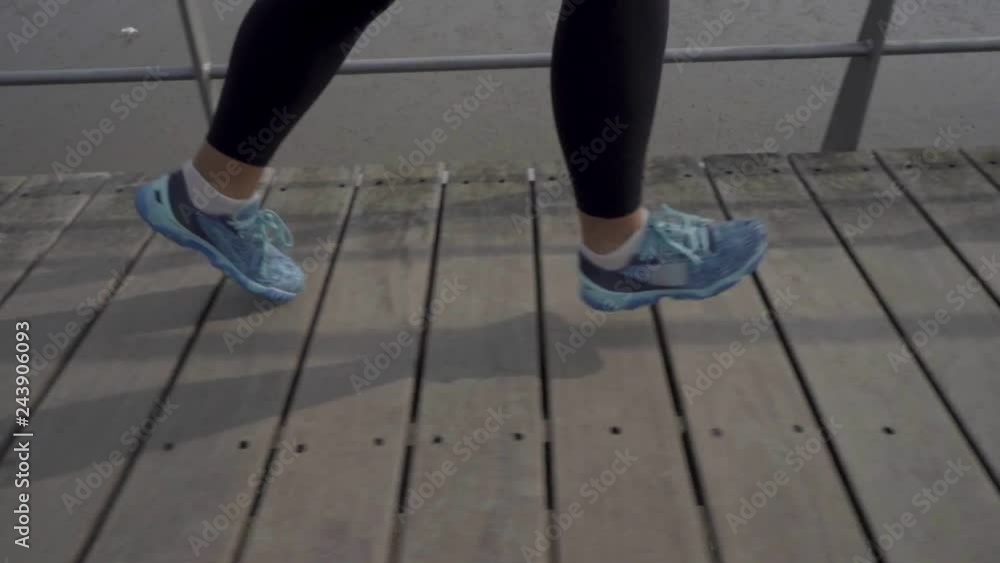 Confident sporty female runner training outdoor. Side view of young woman running on wooden jetty. Concept of sport Confident sporty female runner training outdoor. Side view of young woman running on wooden jetty. Concept of sport