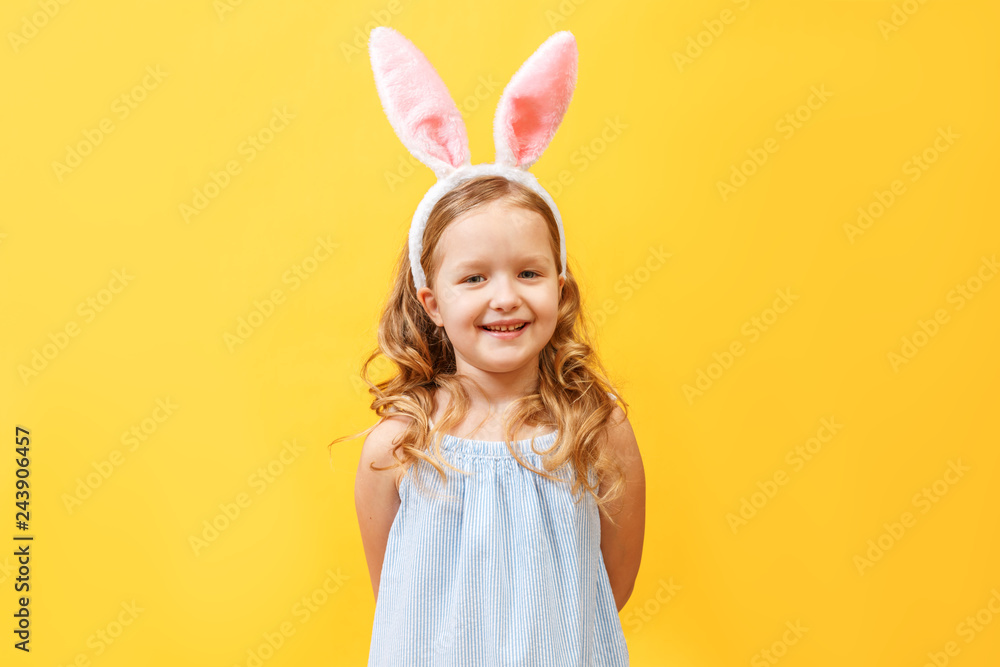 Portrait of a cute little child girl with bunny ears on a colore