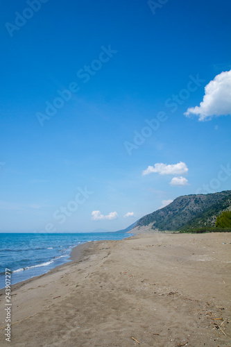 Beach, sand and sea against a bright blue background and rock