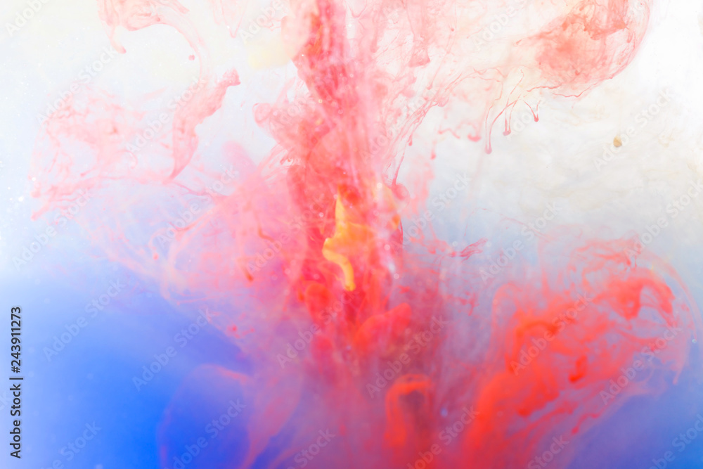 blurred red, purple and blue ink color dropping in water abstract background