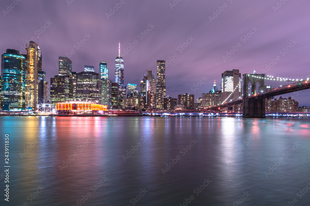 View on Financial district with Brooklyn bridge from east river at night with long exposure