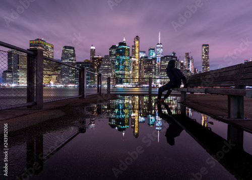 View on Financial district from the pier with man on the bench and water reflection at night with long exposure