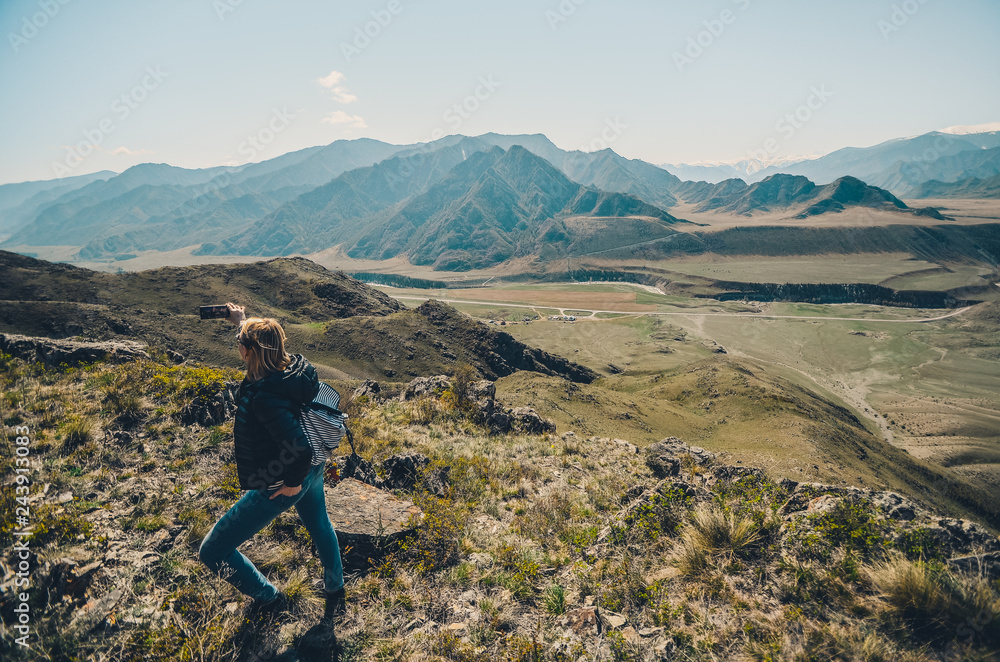 Girl tourist photographs mountain scenery. Selfies in the Altai Mountains. Chui tract, Altai. Valley Chuya.