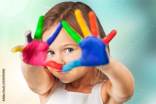 Cute little girl with colorful painted hands on class background