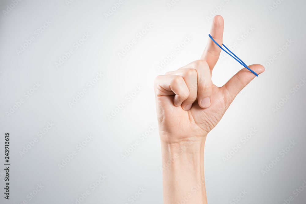 Hand playing with elastic hair band on gray background Hand playing with elastic hair band on gray background