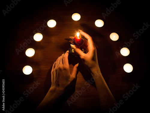Candles and female hands with sharp nails. Divination and witchcraft, low key.