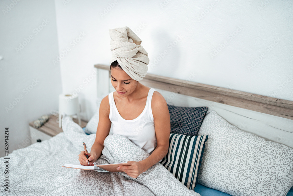 Young woman writing a diary in the bed. Young woman writing a diary in the bed.