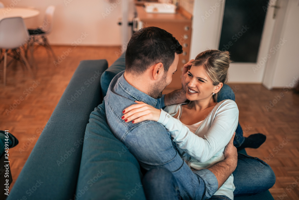 Happy couple cuddling on the sofa and looking into each other's eyes with love. Happy couple cuddling on the sofa and looking into each other's eyes with love.