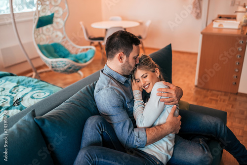 Quadro em tela Young couple cuddling on the couch at home.
