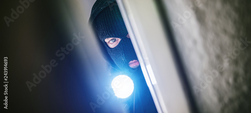 burglar with torch opens door of appartment photo