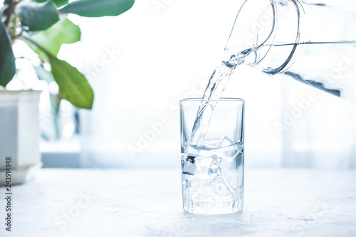 Pouring water on glass on white table