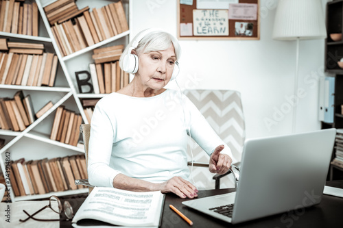 Concentrated mature woman looking at screen of laptop
