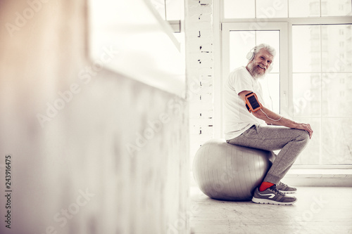 Positive delighted mature man sitting in semi position photo