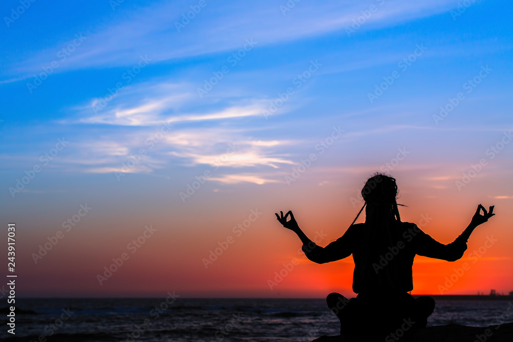 Meditation woman yoga silhouette, ocean during amazing sunset.