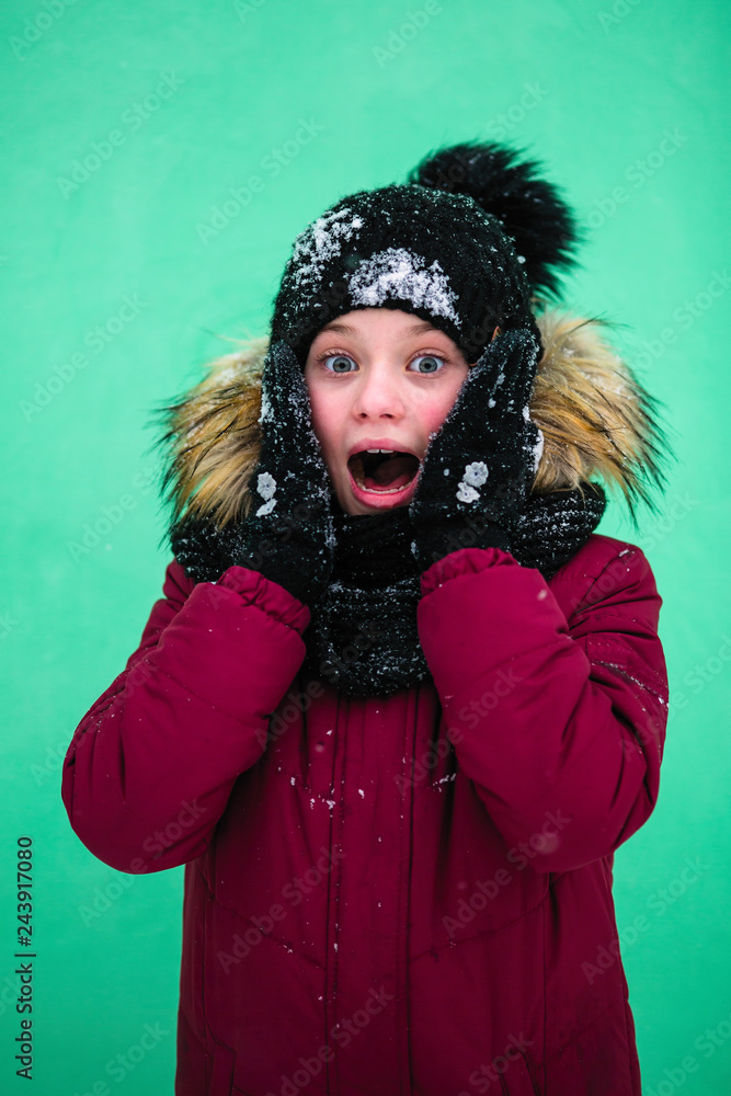 Cute little girl yells in surprise in the winter near the wall. Cute little girl yells in surprise in the winter near the wall.