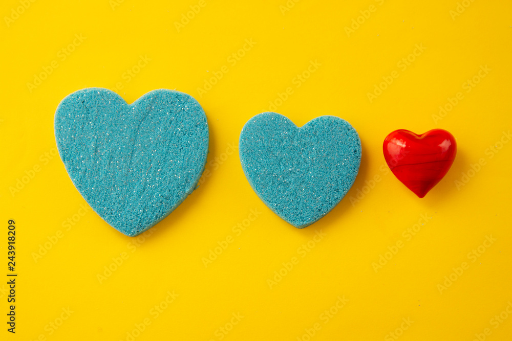 Obraz premium Beautiful blue and red hearts. Greeting ard for Valentine s day. Kinetic sand heart shape, over yellow background. Creative heart and love concept.
