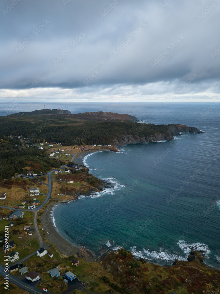 Aerial view of a small town on a rocky Atlantic Ocean Coast during a cloudy day. Taken in Paradise, Twillingate, Newfoundland, Canada.