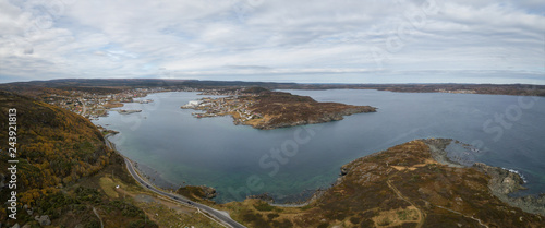 Aerial panoramic view of a small town on a rocky Atlantic Ocean Coast during a cloudy day. Taken in St. Anthony, Newfoundland, Canada. © edb3_16
