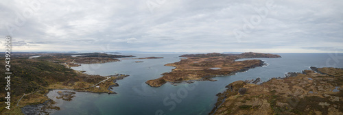 Aerial panoramic view of a small town on a rocky Atlantic Ocean Coast during a cloudy day. Taken in Quirpon, Newfoundland, Canada.