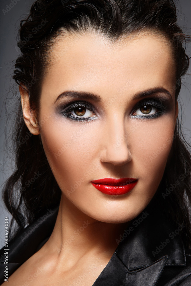 Portrait of young beautiful brunette with smoky eye make-up and red lips