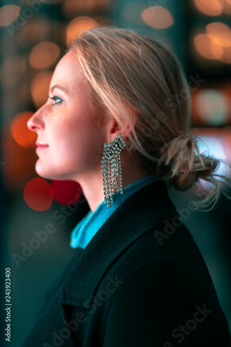 Side profile of a young blonde woman in low light looking into a shop window