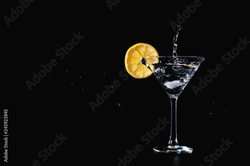 Cocktail water drink splash in the glass with lemon Isolated on black