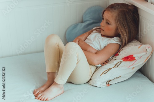 Little girl in her bed has a stomachache.