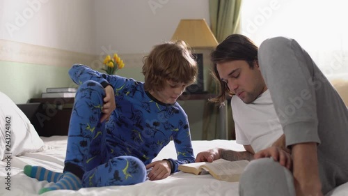 Older and younger brothers in pajamas lying on the bed in the bedroom in the morning. photo