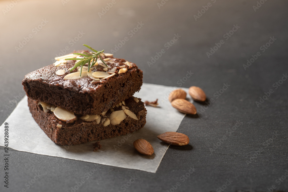 Homemade dark chocolate brownies topping with almond slices stacked on dark plate with copy space. Delicious bitter sweet and fudge. Brownie is one type of chocolate cake.