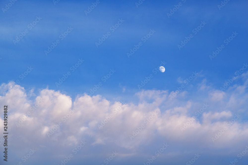 The moon in the sky in the daytime with the cloud against the blue sky background. Natural background