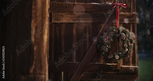 Snow gently falling on rustic barn with christmas wreath. Rustic Christmas scenes while testing out the blackmagic pocket cinema camera 4k