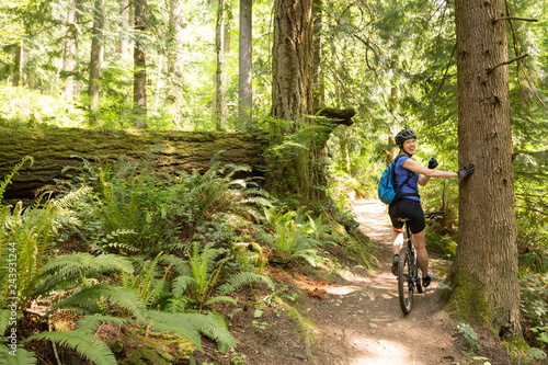 Happy, healthy, smiling woman having fun riding mountain bike biking on a trail. Women's outdoor adventure sports.