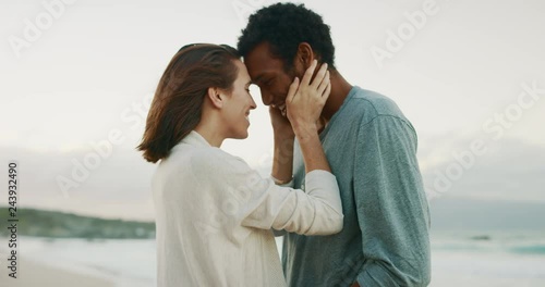 Happy young couple embracing and kissing on tropical beach at sunset