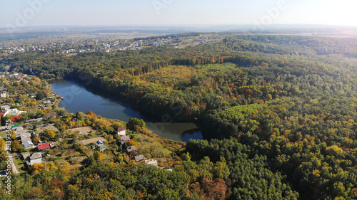 Aerial autumn landscape with village and lake between forest