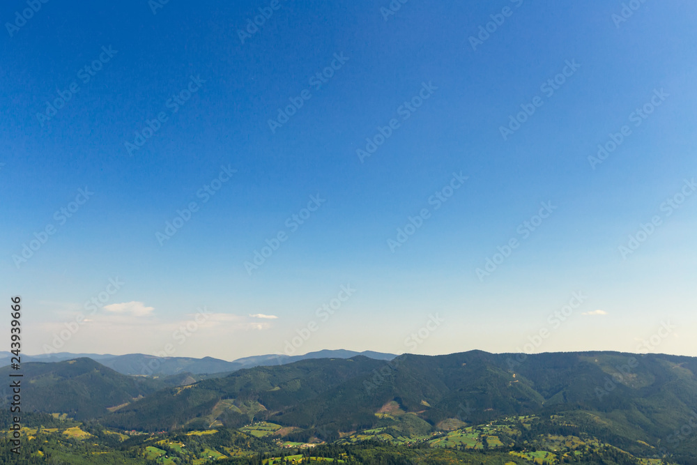 The picturesque mountain range is covered with dense forest and blue sky without clouds